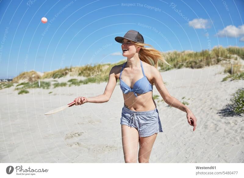 Happy young woman on the beach playing beach paddles vacation Holidays laughing Laughter beaches females women Travel positive Emotion Feeling Feelings