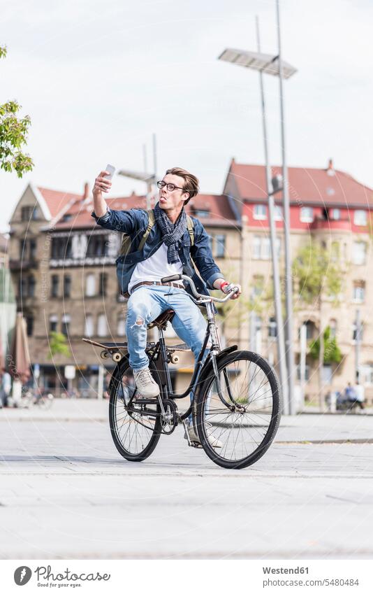 Playful young man with bicycle in the city using cell phone Selfie Selfies mobile phone mobiles mobile phones Cellphone cell phones men males bikes bicycles Fun