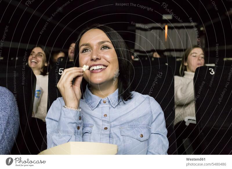 Woman watching a movie in a cinema cinemas sitting Seated woman females women eating spectator spectators Popcorn Popcorns entertainment Adults grown-ups