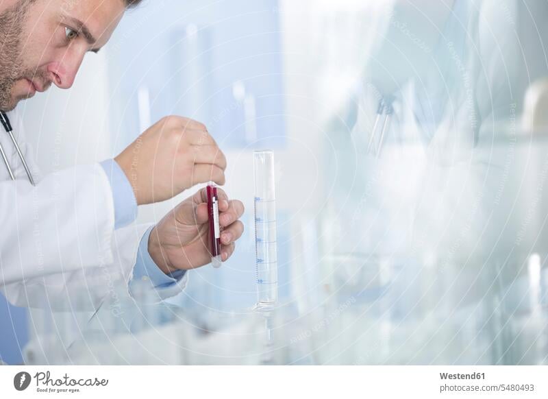 Man examining test tube with liquid in laboratory testing laboratory technician Lab Tech working At Work science sciences scientific checking Test Check