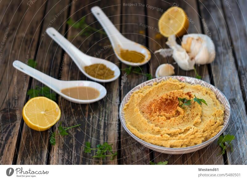 Bowl of Hummus and ingredients on wood food and drink Nutrition Alimentation Food and Drinks wooden spoon wooden spoons hearty savoury food lusty dark wood