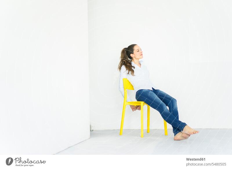Woman sitting on a yellow chair Seated chairs woman females women Adults grown-ups grownups adult people persons human being humans human beings looking away