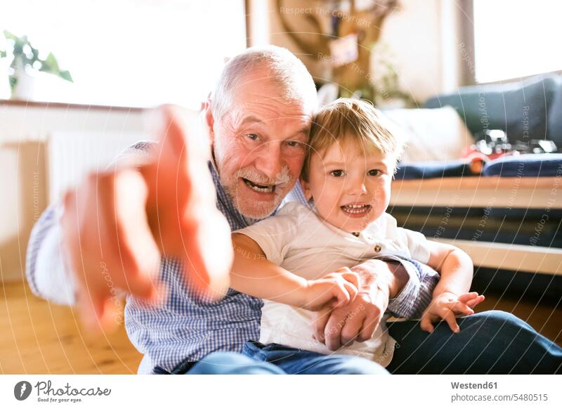 Grandfather and grandson having fun at home together playing playfighting play fighting Romping grandsons grandfather grandpas granddads grandfathers grandchild