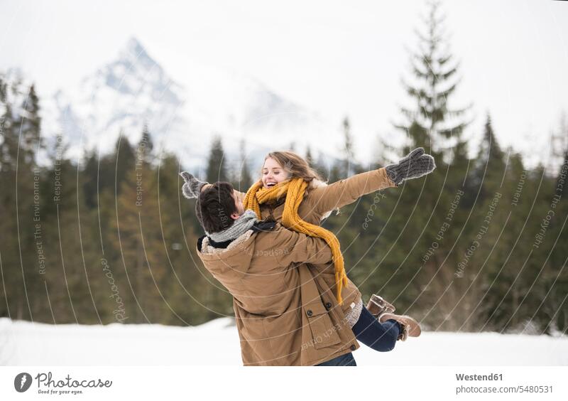 Happy young couple having fun in winter landscape twosomes partnership couples people persons human being humans human beings laughing Laughter Holding Aloft