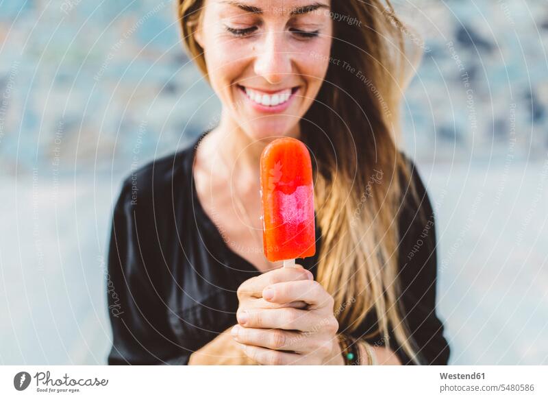 Smiling young woman holding popsicle females women happiness happy Adults grown-ups grownups adult people persons human being humans human beings Sweet Food