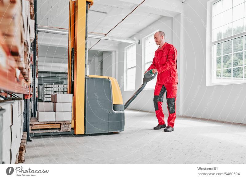 Man in factory using forklift working At Work factories storehouse man men males forklifts forklift truck forklift trucks building buildings Adults grown-ups