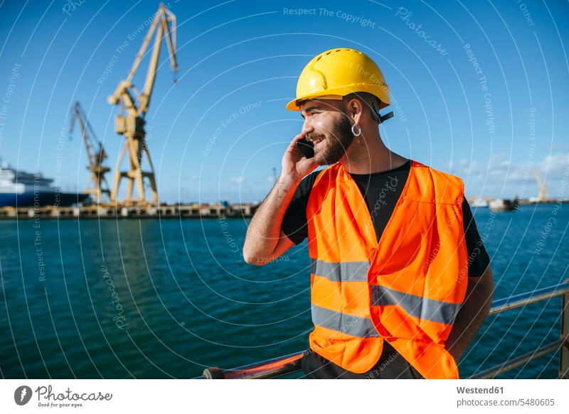 Smiling port worker talking on cell phone smiling smile on the phone call telephoning On The Telephone calling working At Work mobile phone mobiles