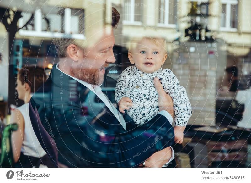 Businessman holding his baby boy in cafe Business man Businessmen Business men portrait portraits father pa fathers daddy dads papa infants nurselings babies