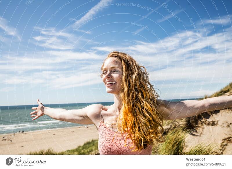 Netherlands, Zandvoort, happy woman standing in dunes with outstretched arms females women beach beaches sand dune sand dunes laughing Laughter Adults grown-ups
