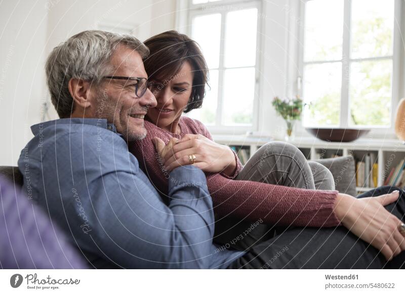Smiling mature couple at home on the sofa couch settee sofas couches settees smiling smile twosomes partnership couples people persons human being humans
