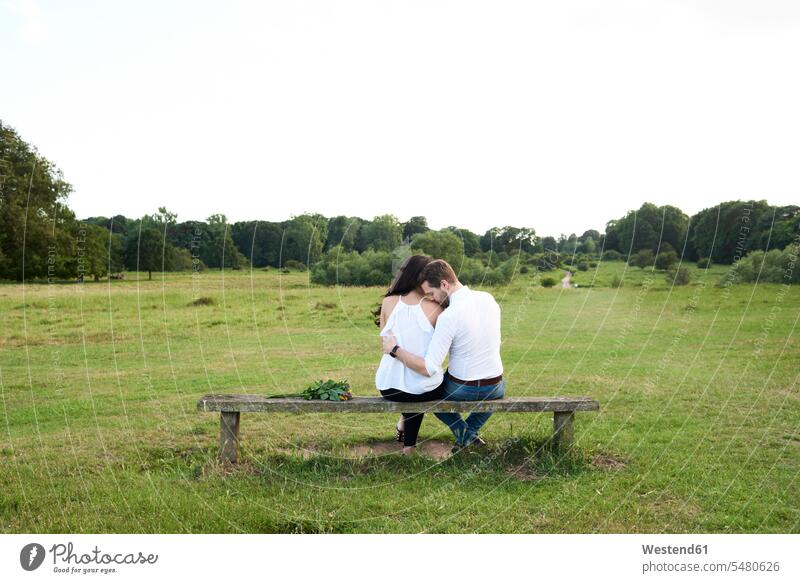 Back view of couple sitting on a bench in a park nature natural world twosomes partnership couples people persons human being humans human beings Seated