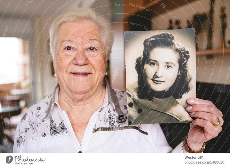 Portrait of senior woman showing an old picture of herself caucasian caucasian ethnicity caucasian appearance european living room living rooms livingroom day