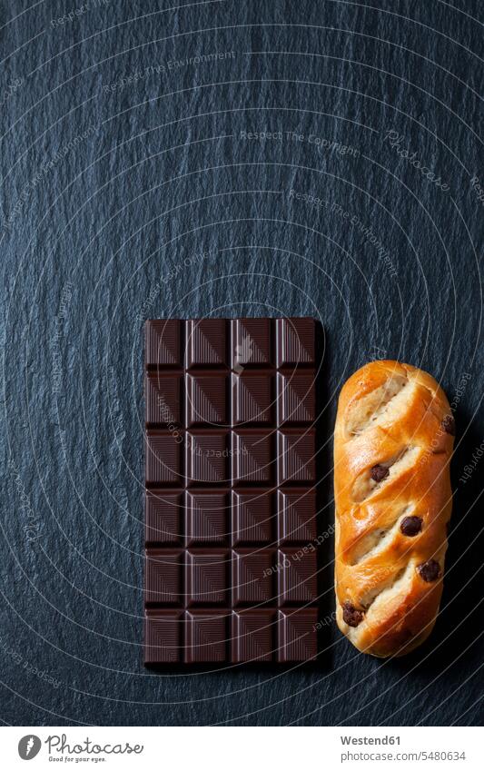 Bittersweet chocolate bar and chocolate bun on slate food and drink Nutrition Alimentation Food and Drinks side by side paralell Juxtaposed in paralell