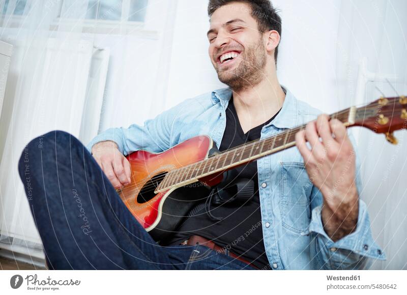Happy young man playing guitar acoustic guitar acoustic guitars classical guitar classical guitars hobby hobbies casual leisure wear casual clothing casual wear