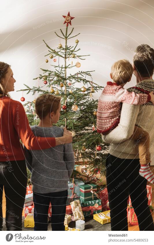 Happy family looking at Christmas tree caucasian caucasian ethnicity caucasian appearance european Christmas Eve Xmas Eve childhood togetherness gifting give