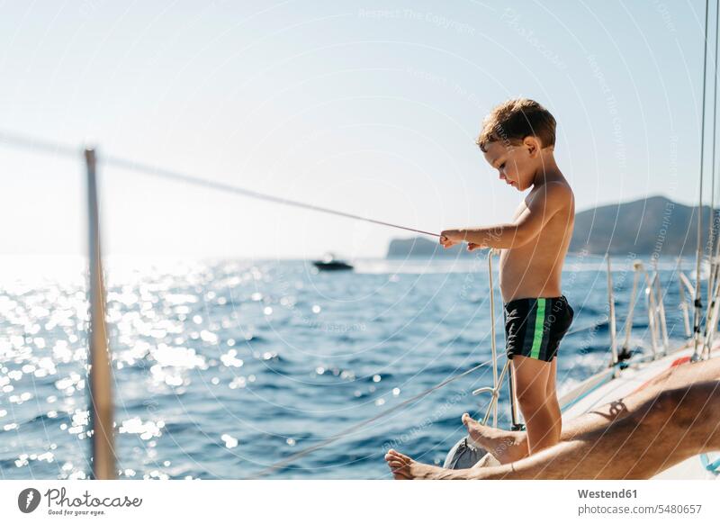 Little boy on a sailing boat standing boats boys males vessel water vehicle child children kid kids people persons human being humans human beings Sea ocean