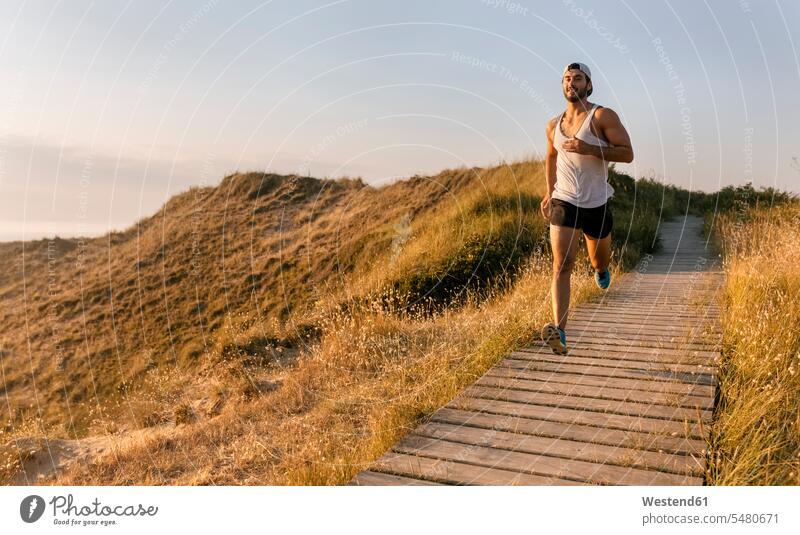 Spain, Aviles, athlete man running along a coastal path at sunset runner runners exercise exercises practising exercising jogger joggers Jogging boardwalk