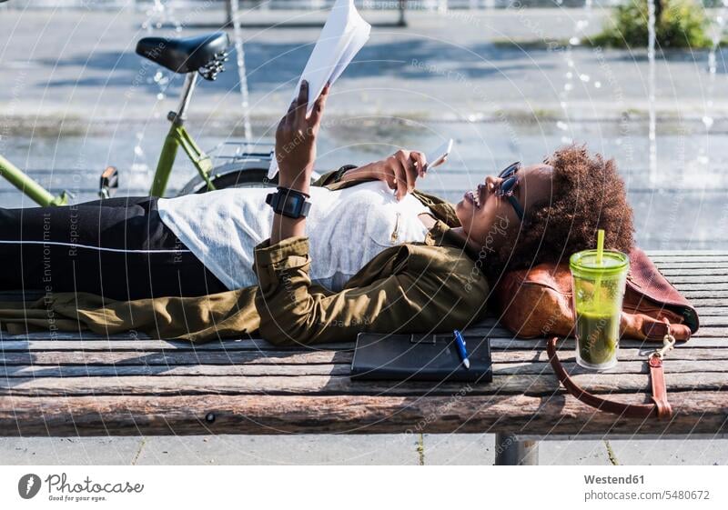 Smiling woman lying on a bench reading notes females women laying down lie lying down Adults grown-ups grownups adult people persons human being humans