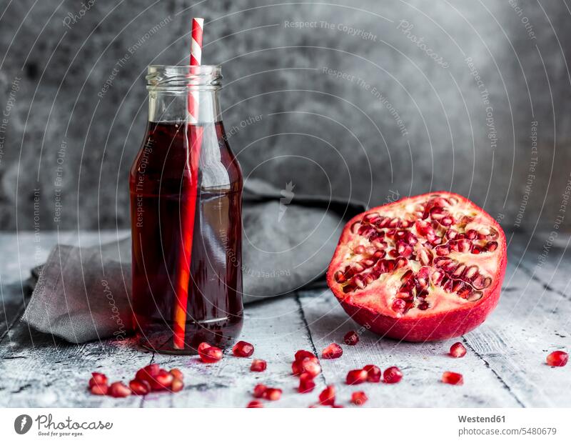 Sliced pomegranate and glass bottle of pomegranate juice Juice Juices fabric fabrics cloth nobody copy space wooden juicy straw straws drinking straw