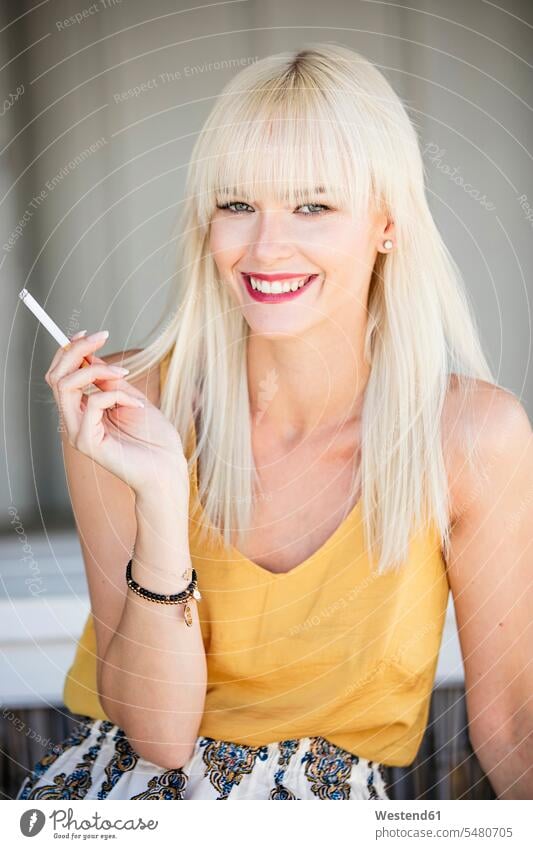 Portrait of smiling blond woman smoking cigarette smoke smile females women Adults grown-ups grownups adult people persons human being humans human beings