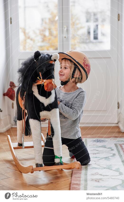 Happy girl playing with rocking horse females girls smiling smile happiness happy rocking horses child children kid kids people persons human being humans
