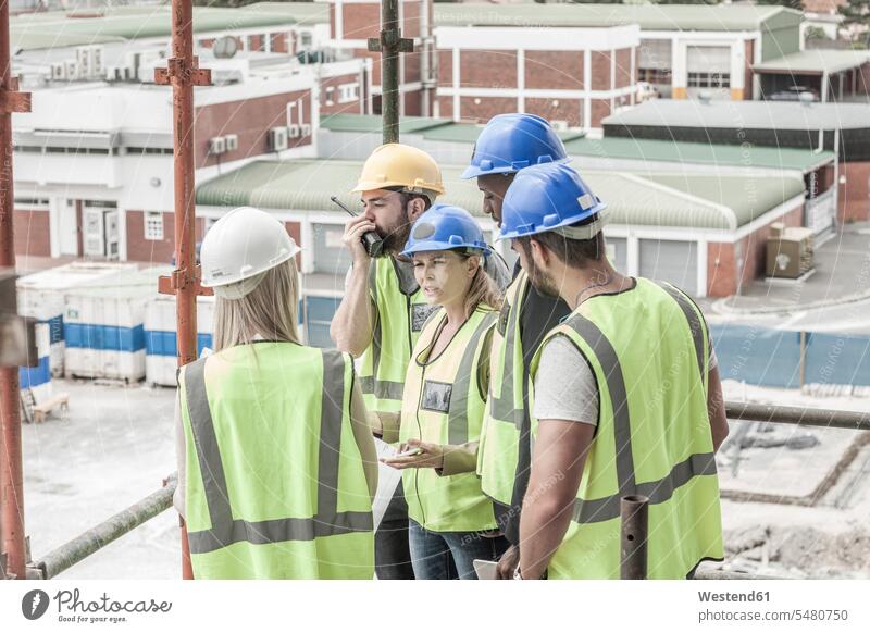 Construction workers and architects talking on construction site work wear work clothes workwear Cooperation working together collaboration Cooperating