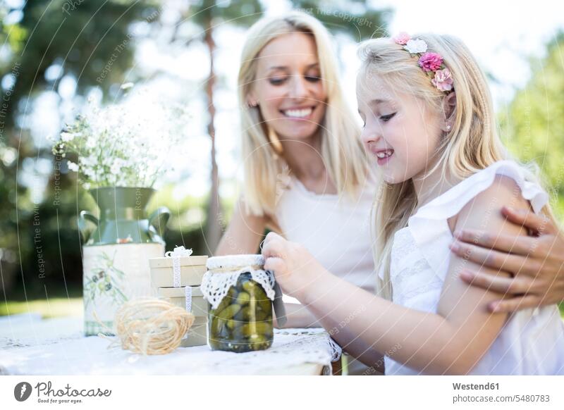 Smiling mother and daughter with preserved gherkins outdoors daughters mommy mothers ma mummy mama smiling smile Gherkin Gherkins child children family families