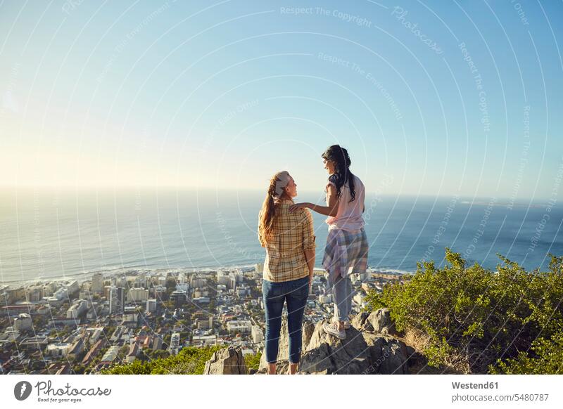 South Africa, Cape Town, Signal Hill, two young women overlooking the city and the sea standing hiking hike View Vista Look-Out outlook female friends woman