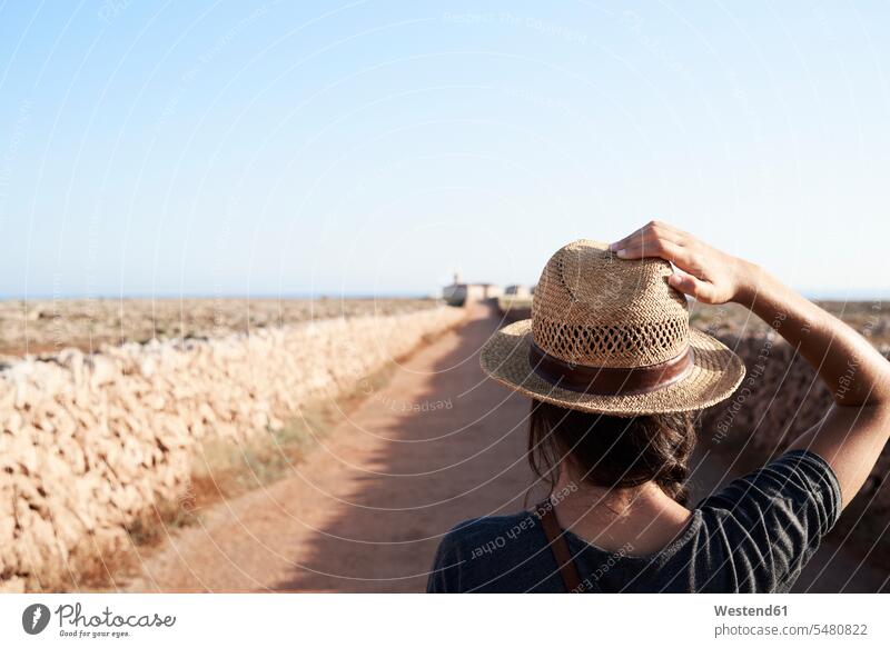 Spain, Menorca, back view of single traveller wearing straw hat woman females women hats solo traveler solo traveller single traveler Adults grown-ups grownups