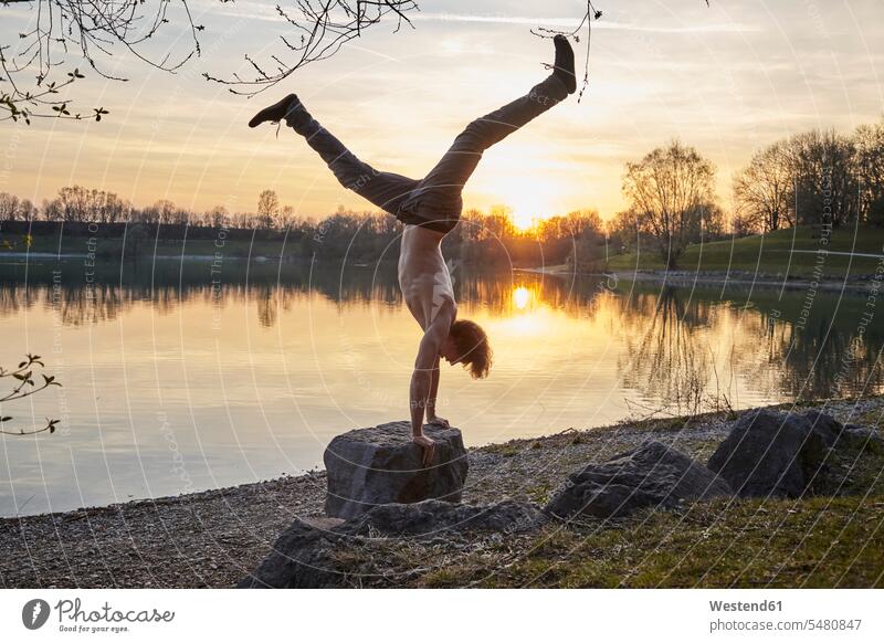 Germany, Bavaria, Feldkirchen, man doing a handstand at lakeshore handstands Parcour men males water waters body of water Adults grown-ups grownups adult people