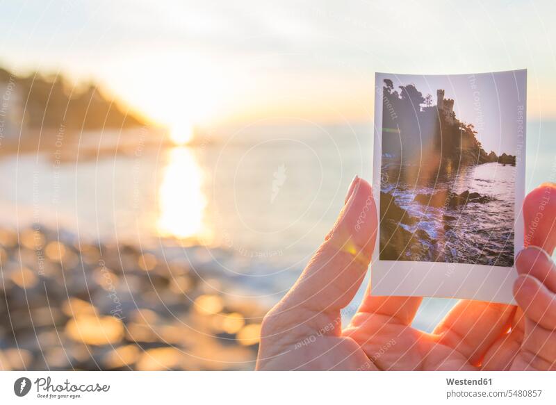 Spain, Costa Brava, Lloret de Mar, woman's hand holding instant photo of Castillo de los Plaja near by human hand hands human hands photograph photographs