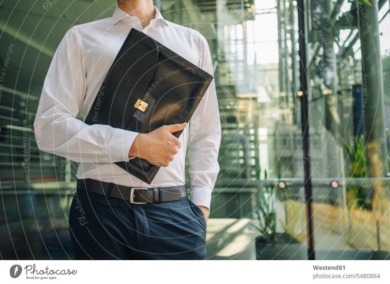 Businessman holding briefcase in lobby business life business world business person businesspeople Business man Business men Businessmen bags brief case human