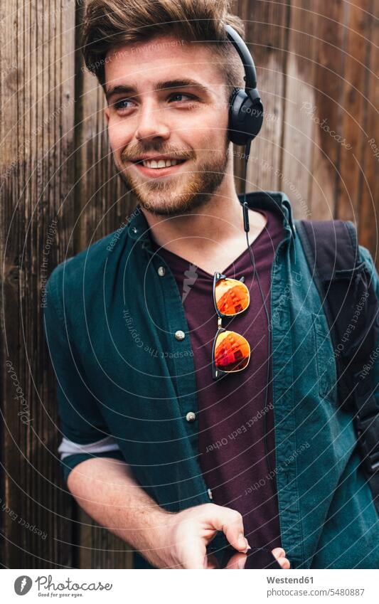 Portrait of happy young man listening music with headphones men males headset Adults grown-ups grownups adult people persons human being humans human beings