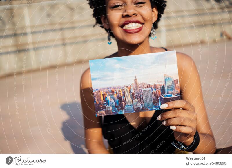 Happy woman showing postcard of New York City picture postcard picture postcards post card post cards females women Showing mail Adults grown-ups grownups adult