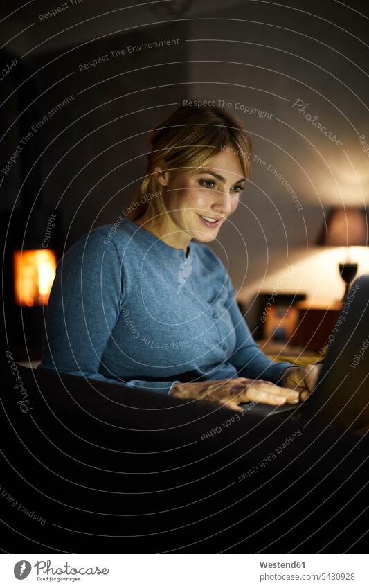 Portrait of smiling woman using laptop at home in the evening smile females women portrait portraits use Laptop Computers laptops notebook Adults grown-ups