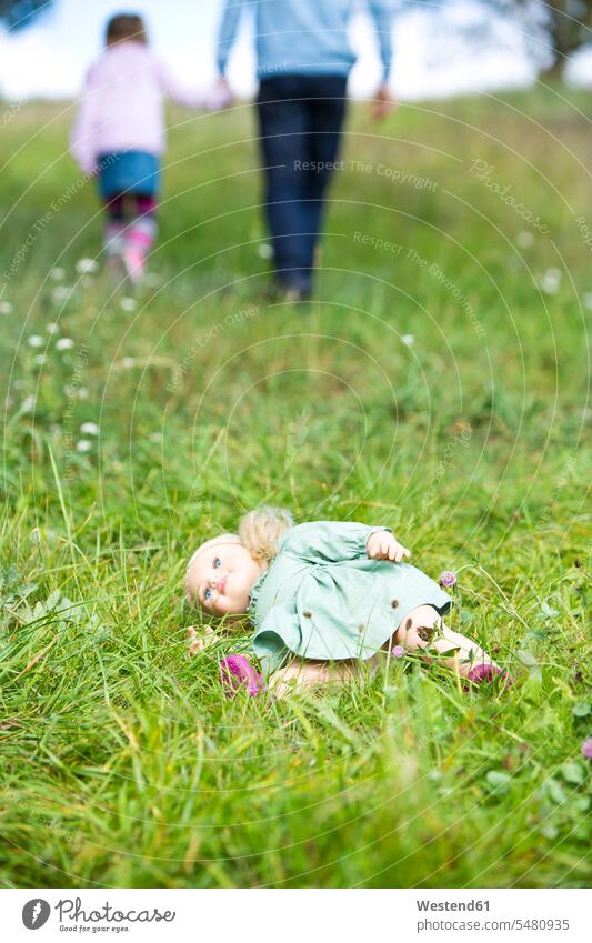 Doll lying on meadow while man going away with little girl caucasian caucasian ethnicity caucasian appearance european on the move on the way on the go