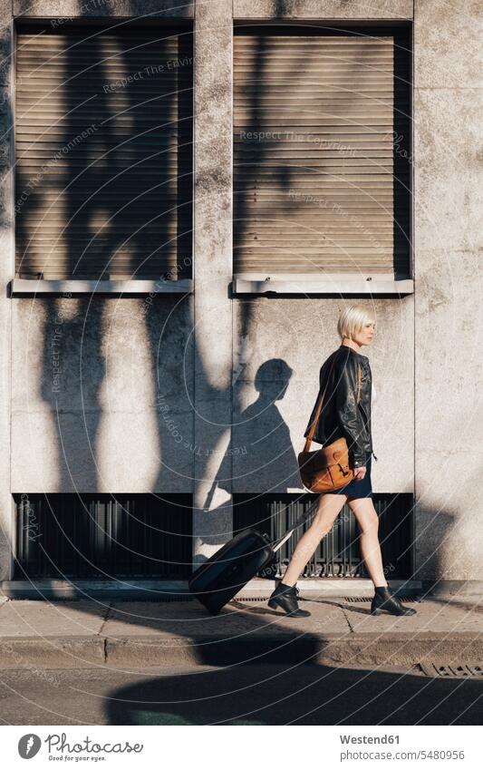 Blond woman with luggage walking on a pavement caucasian caucasian ethnicity caucasian appearance european on the move on the way on the go on the road