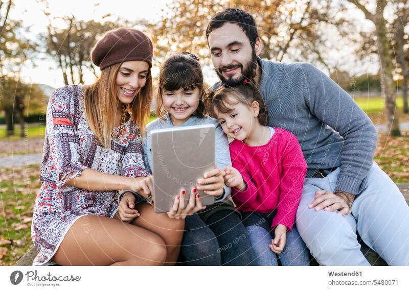 Family sitting on bench in autumnal park taking selfie with tablet family families digitizer Tablet Computer Tablet PC Tablet Computers iPad Digital Tablet