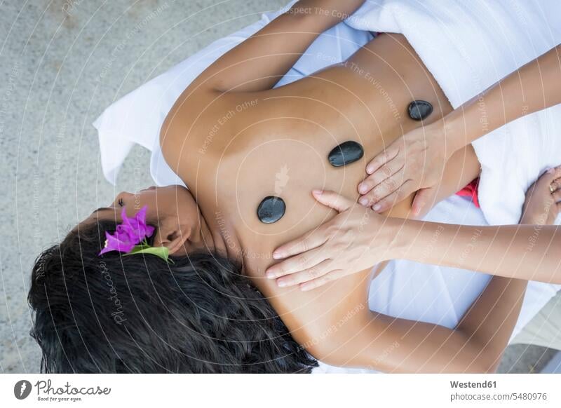 Young woman receiving a massage with heated stones on her back wellness wellbeing females women massage therapy Adults grown-ups grownups adult people persons
