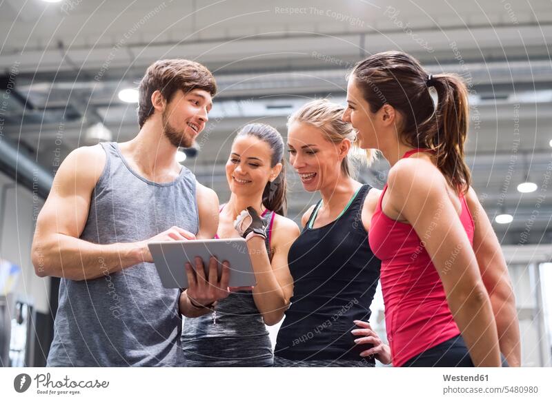 Group of happy athletes with tablet after exercising in gym looking eyeing smiling smile exercise training practising digitizer Tablet Computer Tablet PC