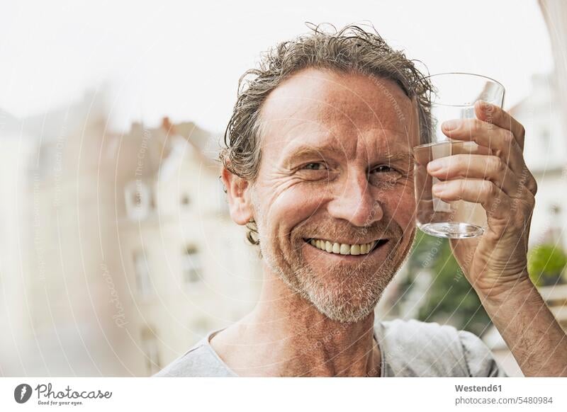 Portrait of smiling man toasting with water glass Glass Drinking Glasses smile portrait portraits drinking balcony balconies Water beverages Drinks Beverage