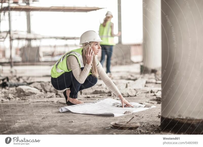 Woman in protective workwear on cell phone in construction site caucasian caucasian ethnicity caucasian appearance european construction industry
