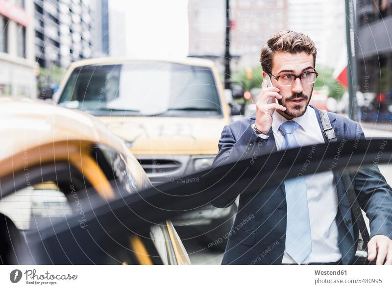 USA, New York City, businessman in Manhattan on cell phone entering a taxi Taxies mobile phone mobiles mobile phones Cellphone cell phones men males