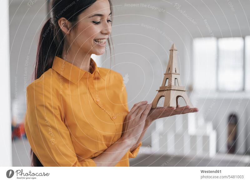 Young woman with model of the Eiffel Tower planning trip to Paris females women Travel holding young Adults grown-ups grownups adult people persons human being