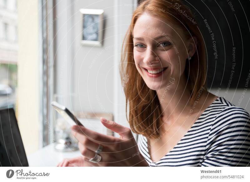 Portrait of redheaded woman with smartphone in a coffee shop portrait portraits smiling smile Smartphone iPhone Smartphones females women mobile phone mobiles