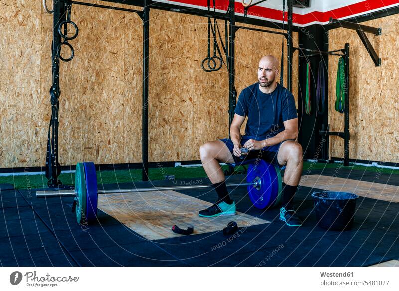 Man resting on barbell in gym exercising exercise training practising man men males gyms Health Club Adults grown-ups grownups adult people persons human being