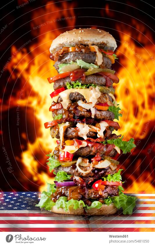 Extra large hamburger on US flag against burning flalmes beef Cheese Gherkin Pickled Gherkins American Flag American Flags Flag of America Flame Blaze flags