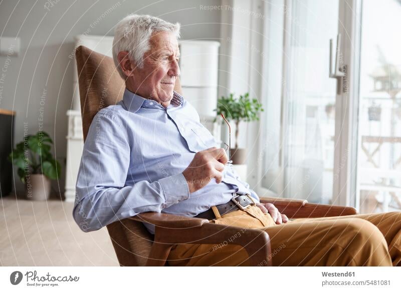 Portrait of senior man sitting on armchair at home looking through window caucasian caucasian ethnicity caucasian appearance european confidence confident