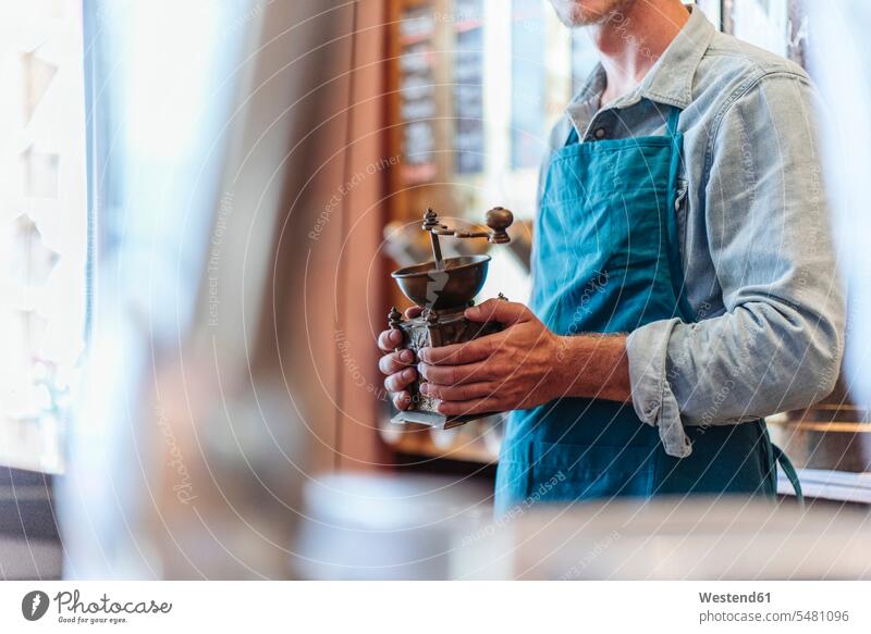 Coffee roaster in his shop holding old-fashioned coffee mill man men males coffee grinder retail trade trading Adults grown-ups grownups adult people persons