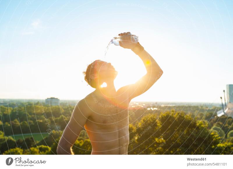 Barechested athlete pouring water over his face at sunset man men males Water Adults grown-ups grownups adult people persons human being humans human beings